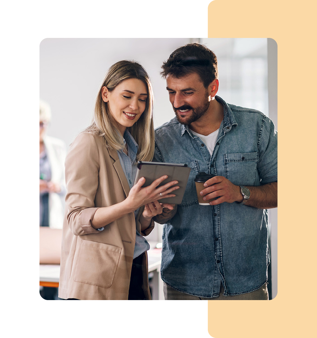 Image of two colleagues conversing and working on a tablet