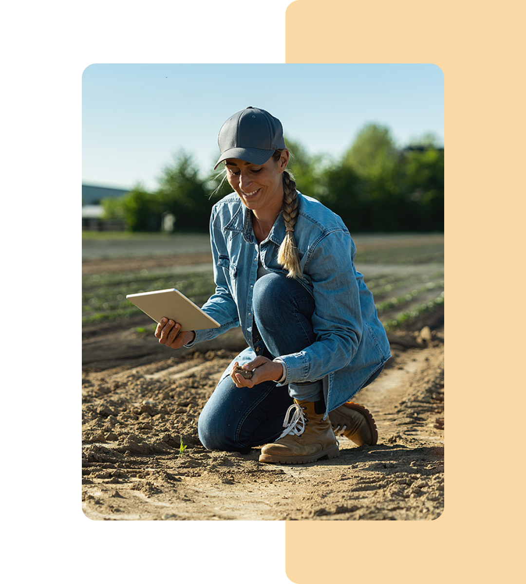 Image of a farmer kneeling in a field holding a tablet