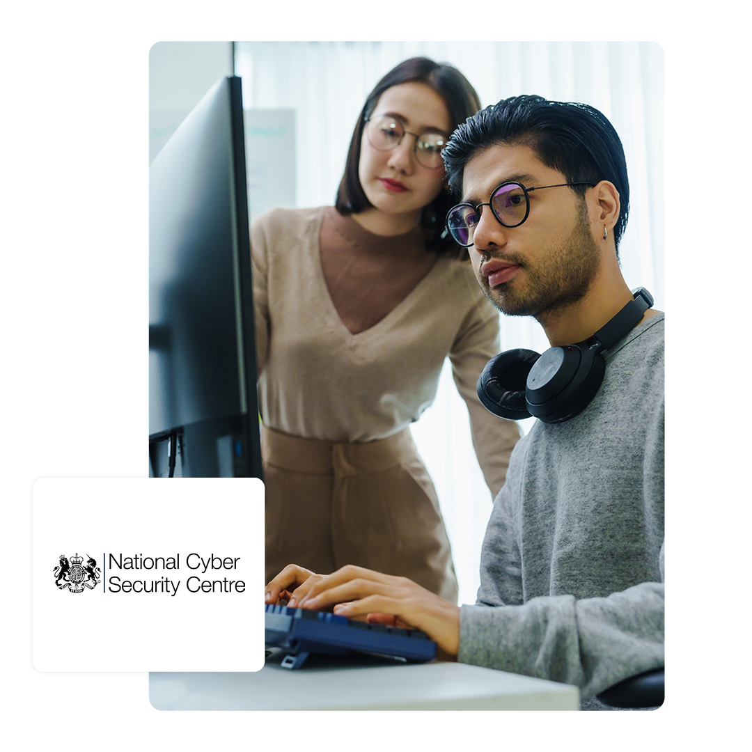 Two people working on a laptop together with a NCSC logo