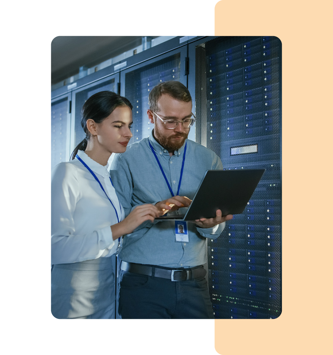 Image of two IT professionals holding a laptop in a data storage room