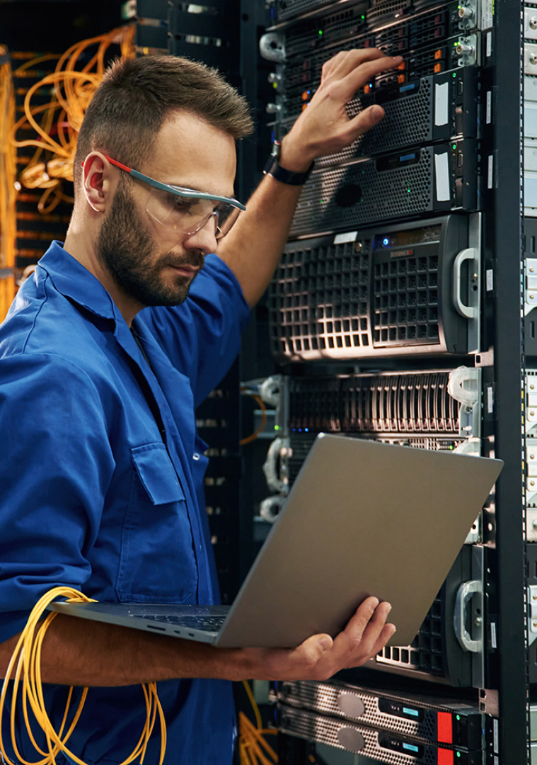 Image of an IT professional working on a server rack holding a laptop