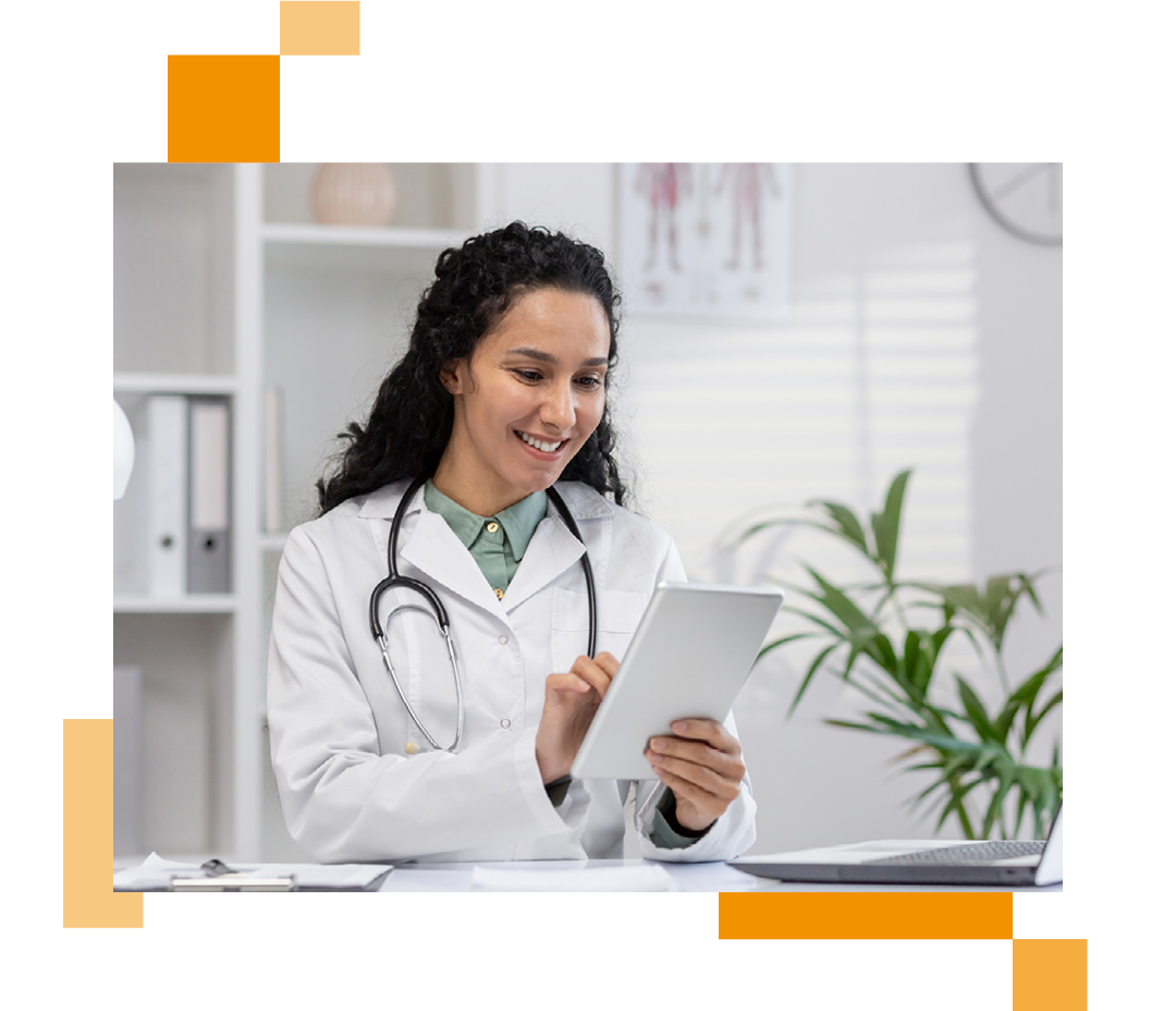 Image of a smiling doctor sat at a desk working on a tablet