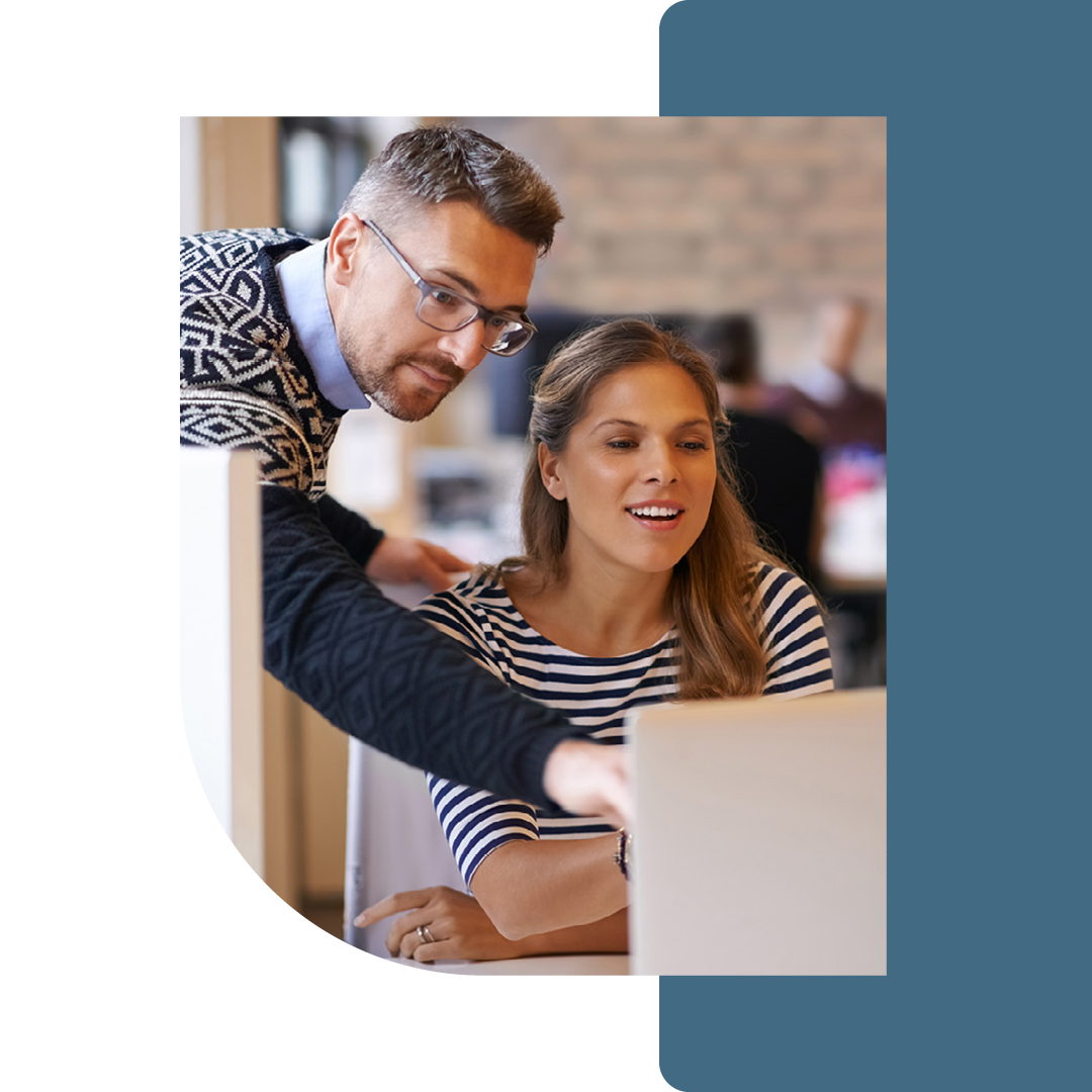 Image of a person helping a colleague working on a laptop