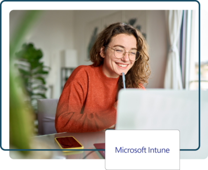 Smiling person working on a laptop remotely with a Microsoft Intune logo