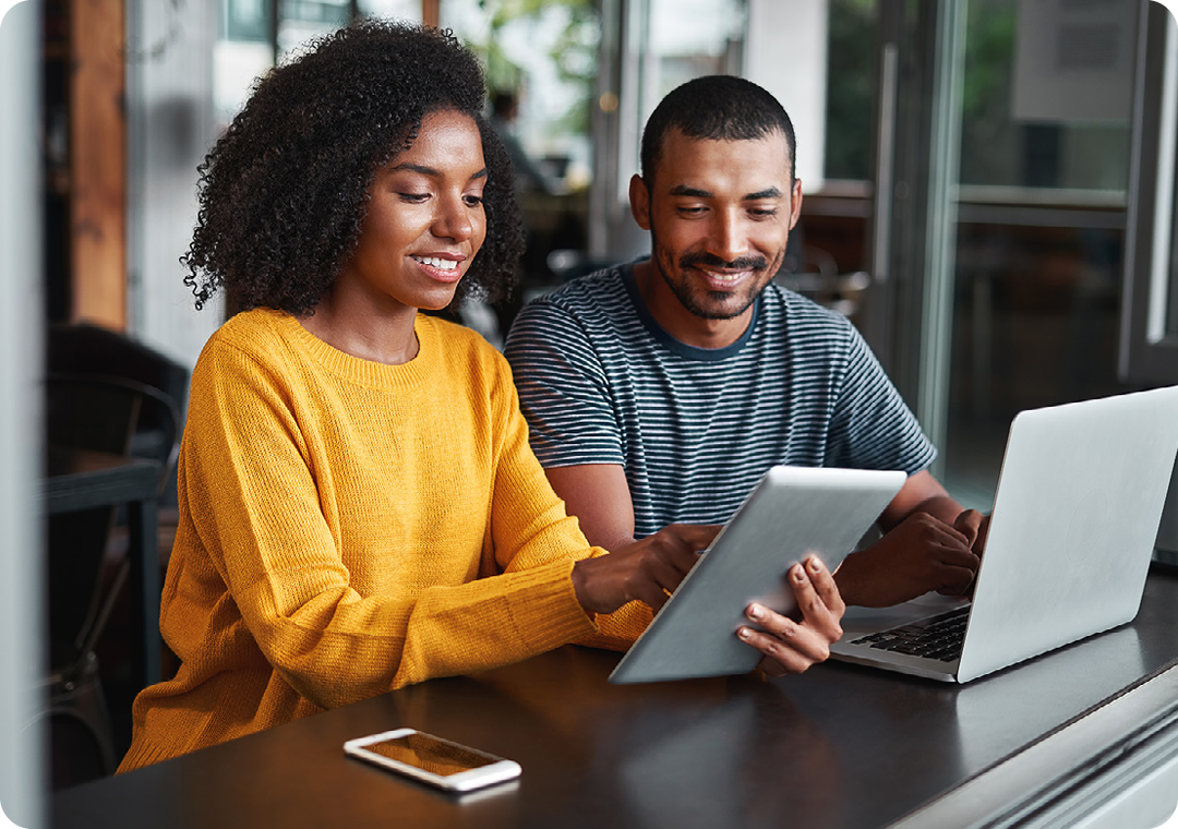 Image of two coworkers working on a tablet and laptop