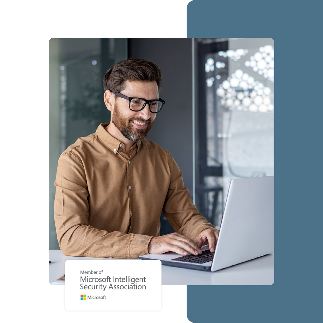 Image of a smiling IT professional working on a laptop with our Microsoft Intelligent Security Association logo