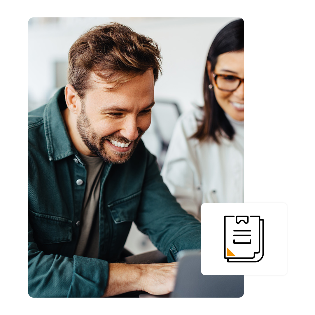 Two people smiling working on a laptop together