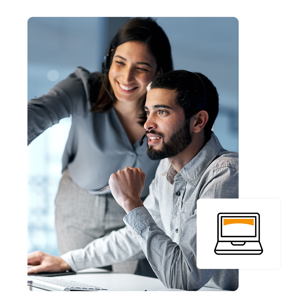 Two people smiling while working on a computer