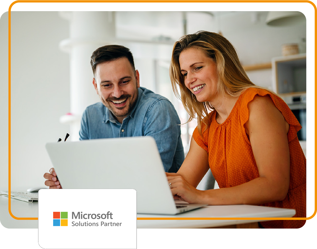 Image of two people sat in an office working on a laptop with Phoenix's Microsoft Solutions Partner logo