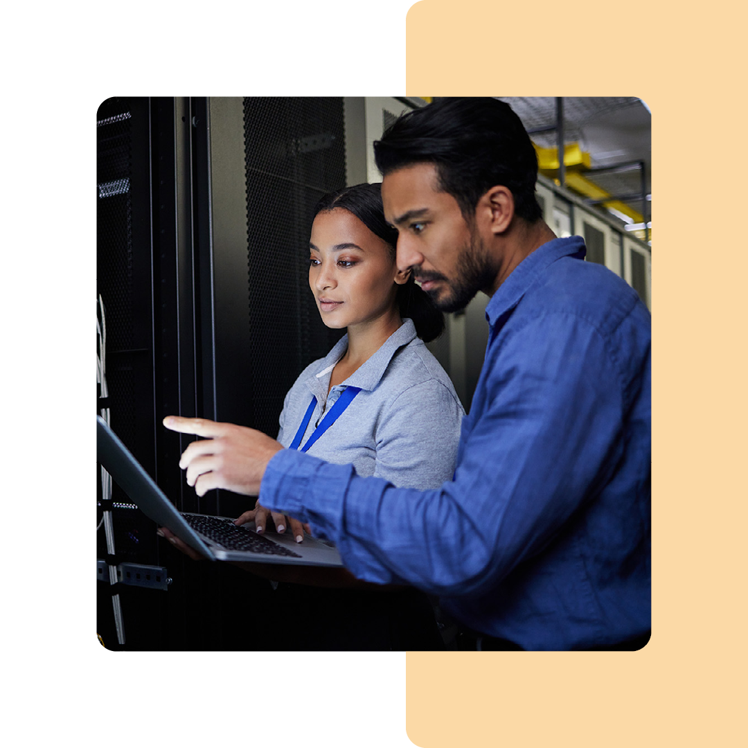 Image of two cyber security professionals working on a laptop in a server room