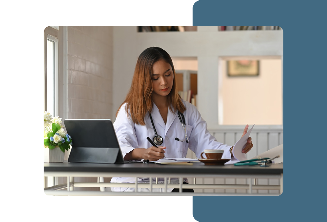 Image of a doctor working at a desk writing in a notepad