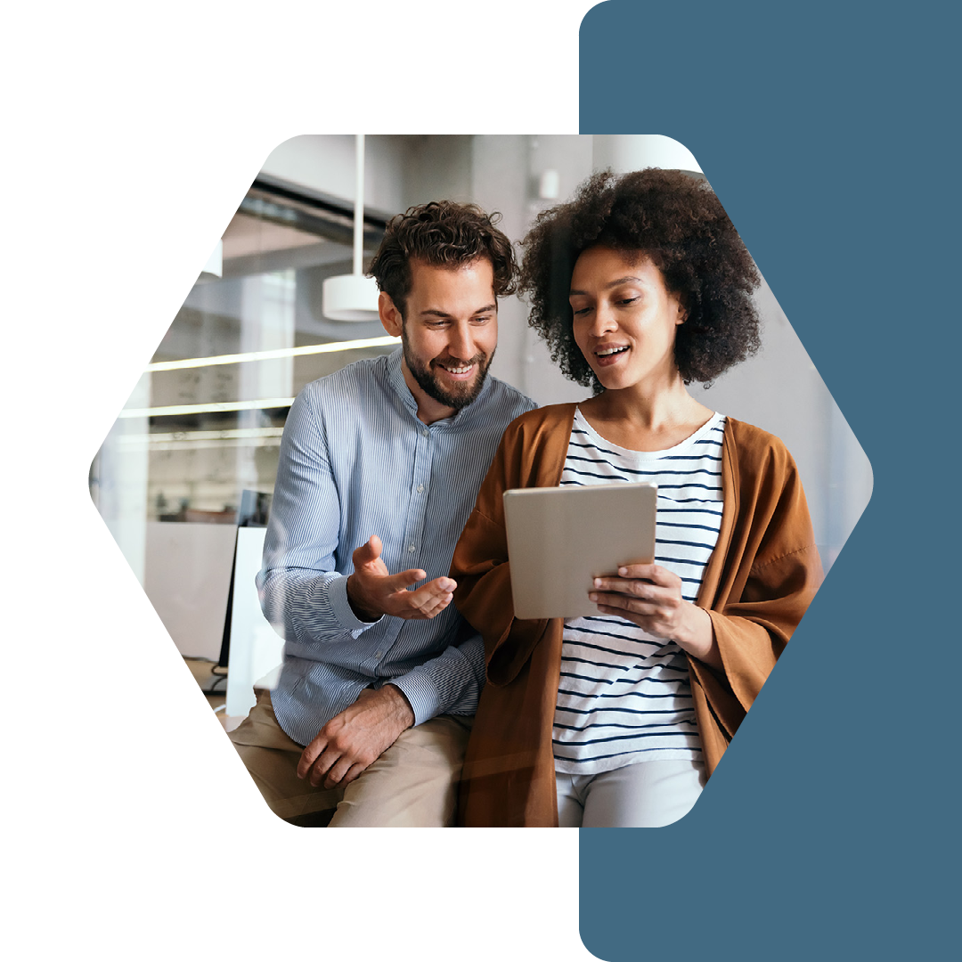 Image of two colleagues talking and working on a tablet together