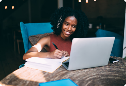 Image of a content writer writing in a notebook and working on a laptop