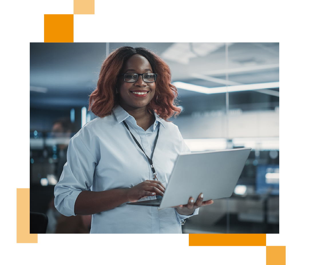 Image of a smiling IT professional stood in a server room holding a laptop