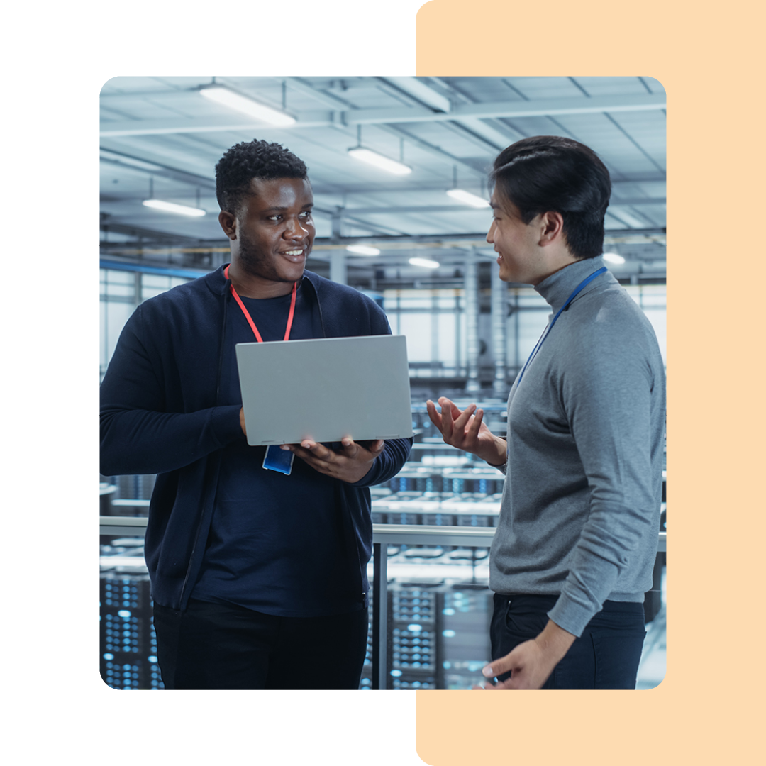 Image of two IT professionals working on a laptop in a server room