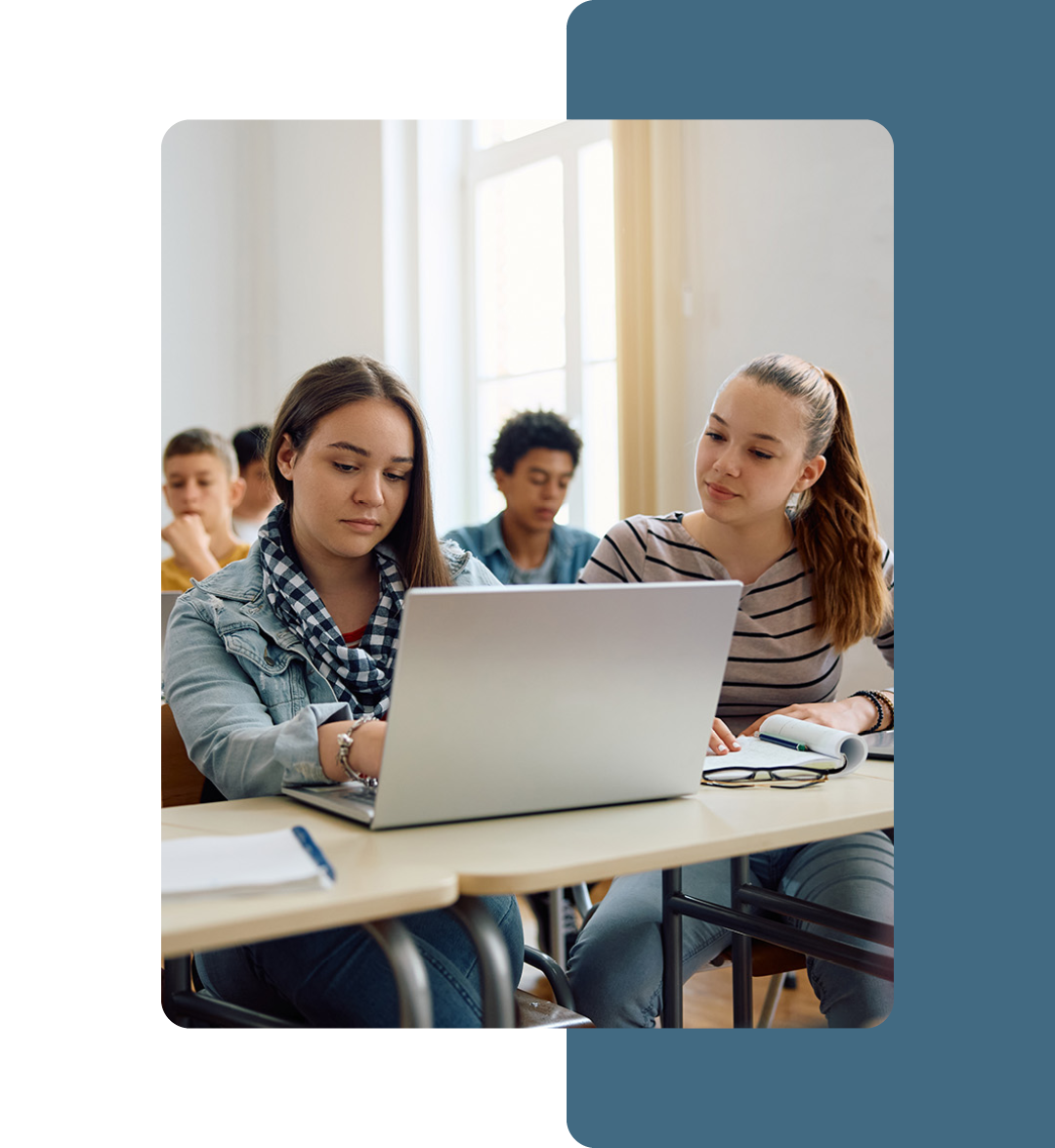 Image of two students sat in a classroom working on a laptop