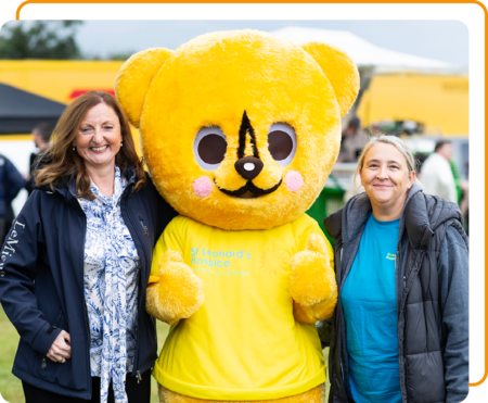 Image of two Phoenix Software employees with the St Leonards Hospice mascot at a Community Event