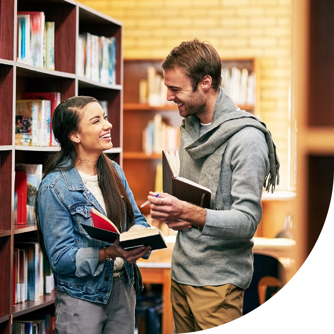 Image of two university students conversing in a library